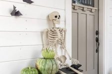 a rustic Halloween porch with heirloom pumpkins, a skeleton and some bats on the wall is a cool idea