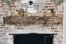a rustic and shabby chic whitewashed brick fireplace with a weathered wood mantel, a beautiful metal screen, greenery and pumpkins for the fall