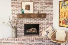 a rustic whitewashed red brick fireplace with a wooden mantel, mid-century modern decor and printed pillows