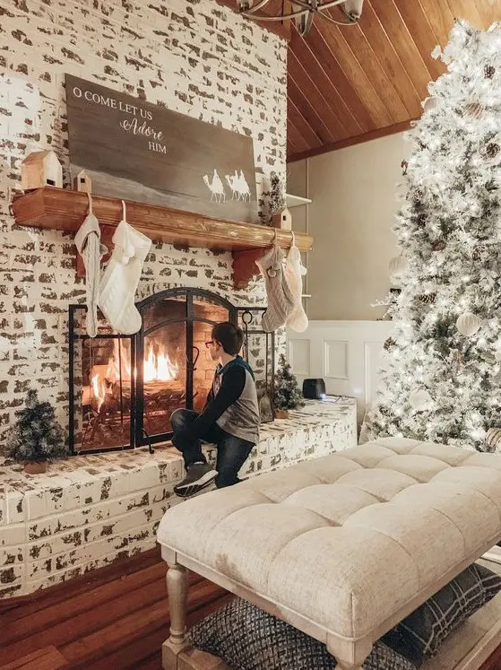 a shabby chic whitewashed brick fireplace with a metal screen, a wooden mantel and some neutral Christmas decor
