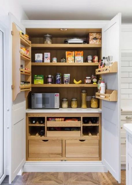 A small built in pantry with stained shelving, drawers and some shelves on the doors is a cool idea for a modern farmhouse kitchen