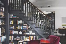 a sophisticated moody space in black, with a staircase featuring a bookcase, a beautiful purple chair for reading here