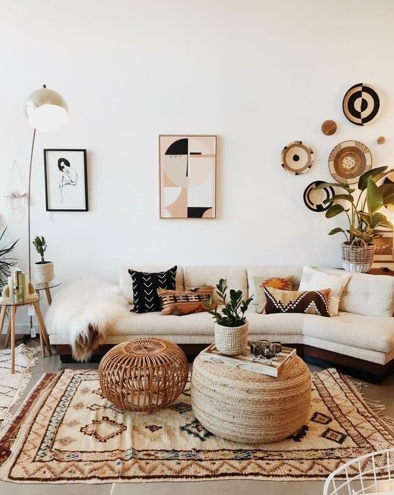 a stylish boho living room with a neutral sofa, a printed rug, a gallery wall featuring artworks and decorative plates