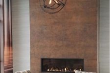a stylish modern living room with a built-in fireplace clad with copper and a metal sphere chandelier looks very cool
