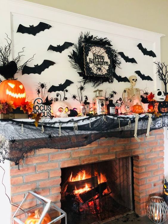 a traditional Halloween mantel with black bats, a black twig wreath, a skeleton, jack-o-lanterns and black spiders and spiderweb