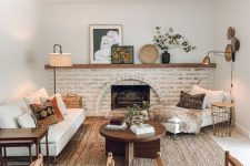 a welcoming earthy living room with a brick fireplace, white seating furniture, brown leather chairs, a coffee table and some decor