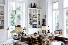 an amazing boho living room done in white, with bookcases and decor, made cozier with a brown leather sofa and a glass coffee table