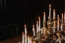 an elegant Halloween centerpiece of skulls, bones, candles, moss and elegant gilded candleholders