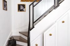 an elegant staircase with stained steps and black frame banister, large drawers built into the stairs