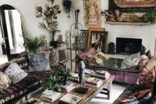 an epic gypsy living room with dark embroidered furniture, pendant lamps, a fireplace and boho pillows and artworks