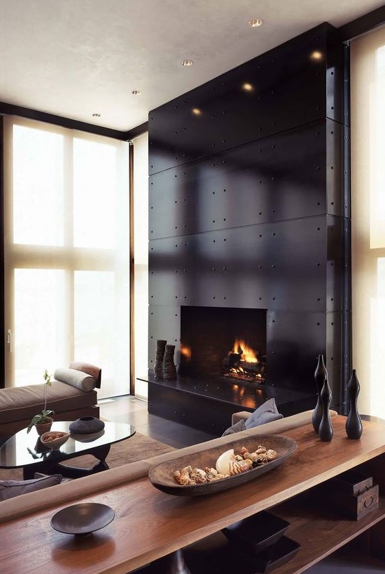 An exquisite living room with a large fireplace clad with black metal, neutral warm colored furniture and black accents