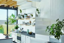 an under the stairs kitchen with open shelves and cabinets and potted greenery is a stylish way to save a lot of space