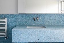 blue terrazzo with navy and white spots covers the walls, floor and the sink stand for texture and color in the space