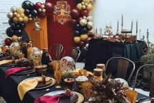 bright Harry Potter Halloween themed party space with bold balloons, a table styled in black, gold and burgundy, with lights