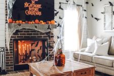 classic Halloween decor with a large TV covered with spiderweb, a fireplace with candles and bats and a lot of spiderweb around