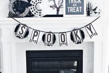 classic black and white Halloween fireplace decor with paper doilies, fake birds, candle lanterns, a bunting and a mini tree
