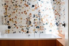 colorful terrazzo with large spots on the walls and floor and a wood clad bathtub