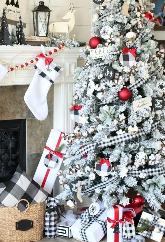 a beautiful flocked Christmas tree with cotton, plaid ornaments, red ones, faux greenery and little sign plaques is amazing