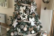 a beautiful rustic Christmas tree with burlap bows and ribbons, fluffy snowflakes, bows, vine ornaments and yarn balls