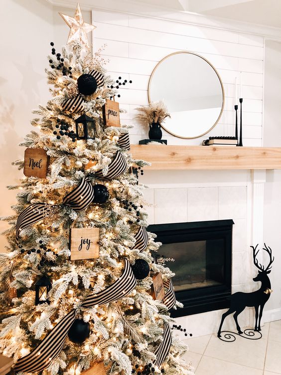 a black and white farmhouse Christmas tree with lights, black and white ribbon, black ornaments and berries