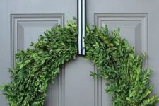 a catchy modern Christmas wreath of boxwood, with a striped ribbon will match many styles and decor themes