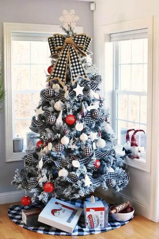 a farmhouse Christmas tree with buffalo check ribbons, red and white printed ornaments, a buffalo check bow and a snowflake on top