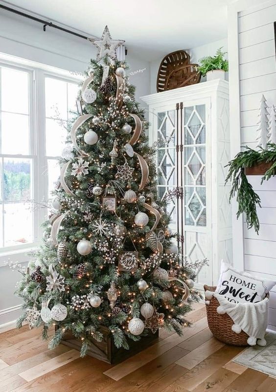 a farmhouse Christmas tree with burlap ribbons, lights, white and silver ornaments, pinecones and snowflakes is a cool idea