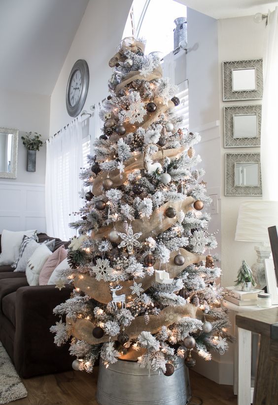 a farmhouse Christmas tree with burlap ribbons, metallic and white ornaments, snowflakes and deer looks magical