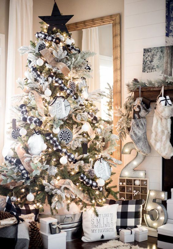 a farmhouse Christmas tree with lights, plaid ornaments, white ones, signs with monograms and a star topper is awesome