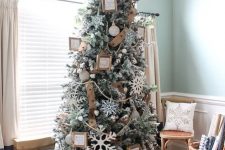 a flocked Christmas tree with belt as a ribbon, wooden signs, snowflakes, wooden beads and a stick star topper