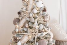 a flocked farmhouse Christmas tree with burlap ribbons, wooden beads, burlap ornaments and white ones plus some snowflakes