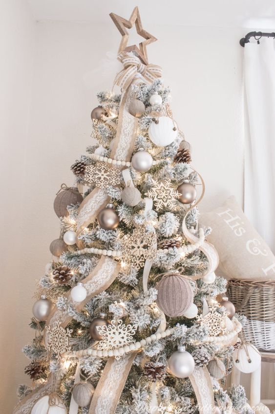 a flocked farmhouse Christmas tree with burlap ribbons, wooden beads, burlap ornaments and white ones plus some snowflakes