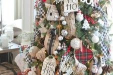 a gorgeous rustic meets traditional Christmas tree with jingle bells, burlap ornaments and buntings, plaid ribbons, yarn balls and fake berries