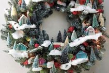 a jaw-dropping modern Christmas wreath of evergreens, little colorful houses and bottle brush trees is wow