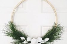 a minimalist Christmas wreath of an embroidery hoop, evergreens and white geometric ornaments is a cool idea