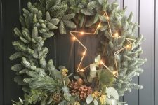 a modern Christmas wreath of evergreens, twigs, greenery, pinecones and a lit up star is a cool and catchy idea