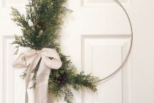 a modern Christmas wreath with evergreens and pinecones on one side and a neutral ribbon bow is a lovely decor idea