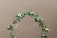 a modern and delicate Christmas wreath with a bit of foliage, baby’s breath and a small lit up house is amazing