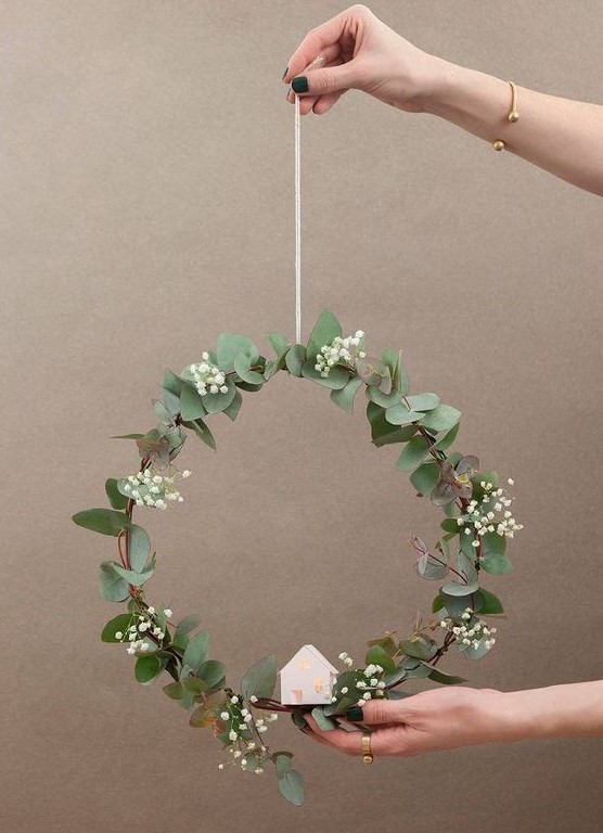 a modern and delicate Christmas wreath with a bit of foliage, baby's breath and a small lit up house is amazing