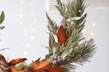 a modern holiday wreath with magnolia leaves, evergreens, berries and leaves is a cool idea for a modern space