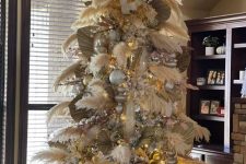 a pampas grass Christmas tree decorated with large metallic ornaments, lights and fronds and topped with some branches