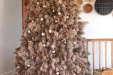 a rustic pampas grass christmas tree decorated with metallic and brown ornaments and lights looks very boho and cozy