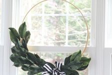 a stylish and timeless modern Christmas wreath done with magnolia leaves and a black and white ribbon bow