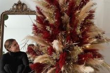 a super bold neutral and burgundy pampas grass Christmas tree decorated with gilded branches and lights is cool for the holidays