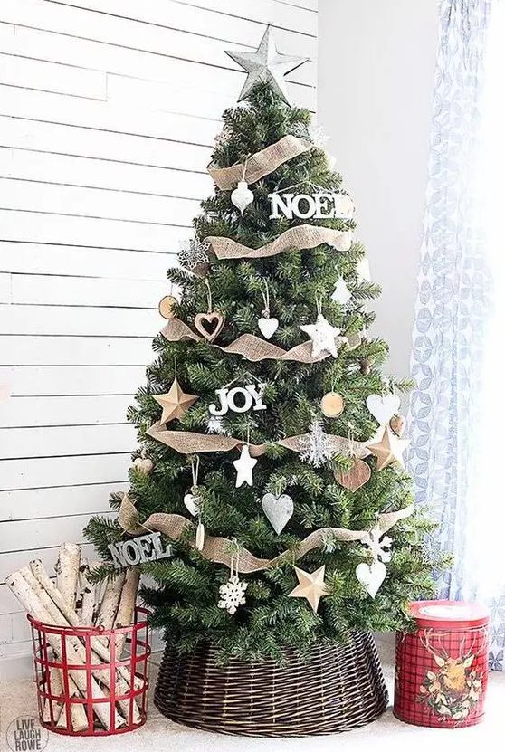 a super cozy Christmas tree with various star ornaments including wooden ones, burlap ribbons, snowflakes and hearts plus a basket cover