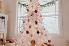 a white Christmas tree decorated with fluffy pompoms of earthy colors and put into a basket to make it look a bit rustic