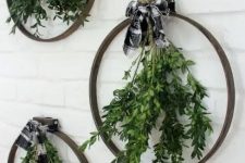 an arrangement of embroidery hoops, with greenery and buffalo check bows on top is a great idea for a modern Christmas space