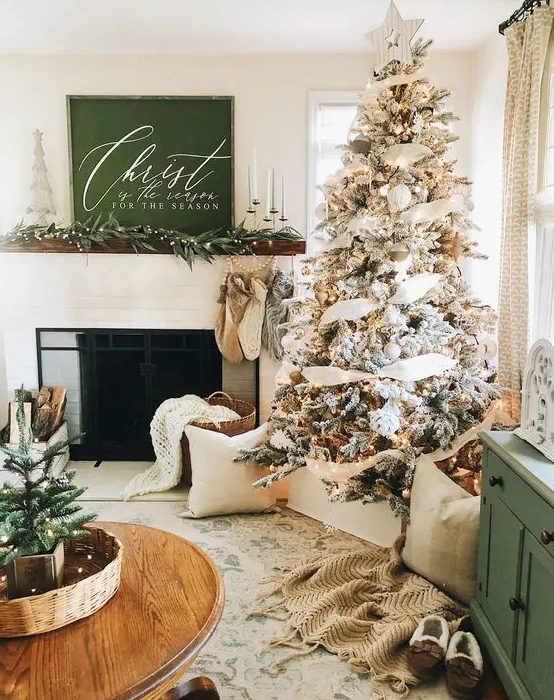 farmhouse and woodland Christmas decor with a flocked Christmas tree with neutral decor, stockings and evergreens