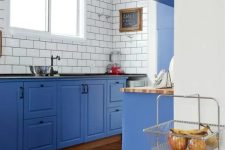 02 a bold blue kitchen with white subway tiles and black grout to stand out plus butcherblock and black countertops