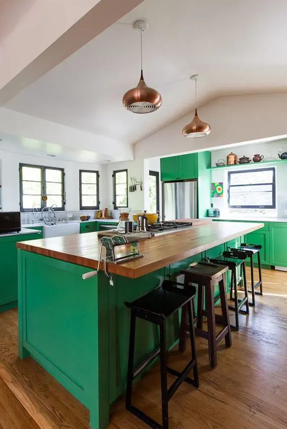 a bold green kitchen is made calmer with neutral countertops and brass touches and black stools